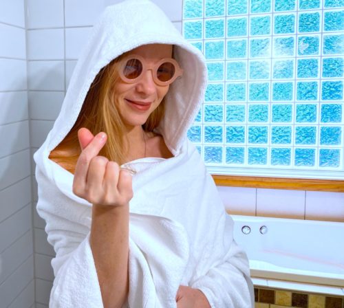 Woman wearing adult-sized white hooded towel.