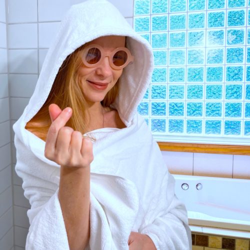 Woman wearing adult-sized white hooded towel.